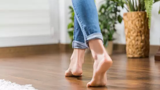 Floor heating. Young woman walking in the house on the warm floor. Gently walked the wooden panels.
