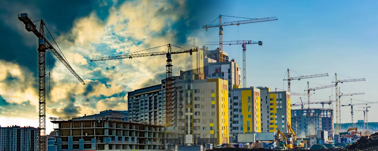 Construction of new buildings, surrounded by cranes, against a cloudy sky; urban view