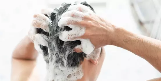Closeup young man washing hair with shampoo in the bathroom, health care concept