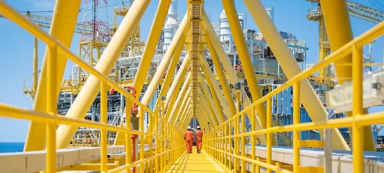 Two workers walking on the connecting bridge between quarter platform and oil and gas central processing platform, offshore oil and gas operation business.