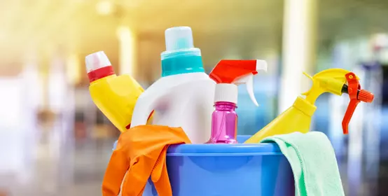 Close up of plastic tub filled with various cleaning supplies