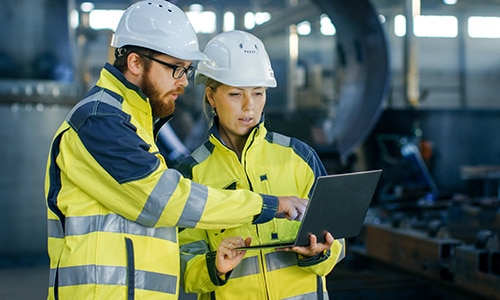 Engineers in a warehouse look at a computer