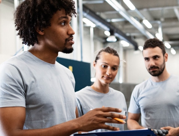Colleagues wearing gray t-shirts meet for a discussion