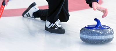 person sliding a curling stone