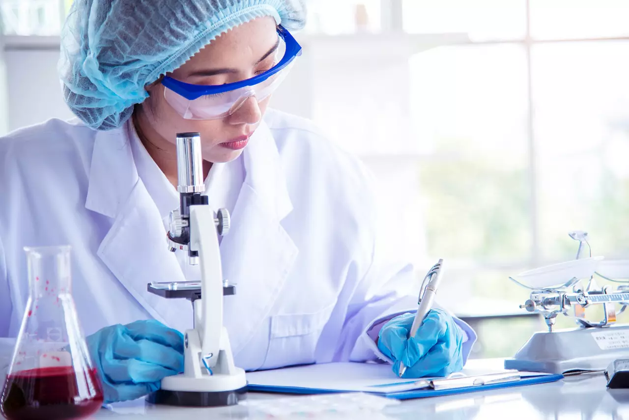 Woman scientist hand write note information in medical lab look at  science microscope medical test