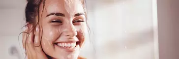 Woman smiles when applying foam for washing on her face