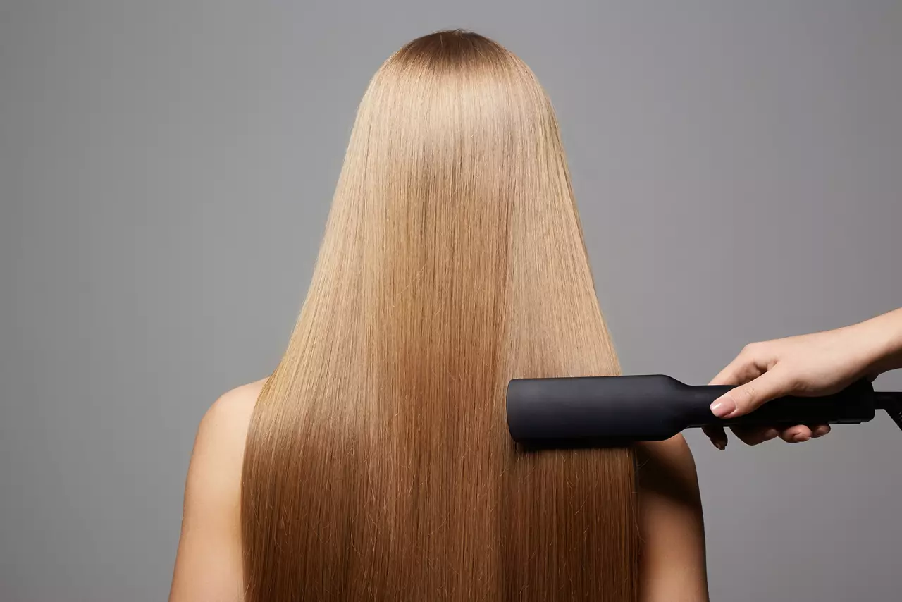 beautiful blond hair woman. Back of girl with Healthy hair. Care and straightening hair with an iron