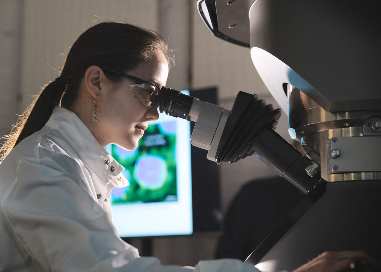female scientist looking in microscope