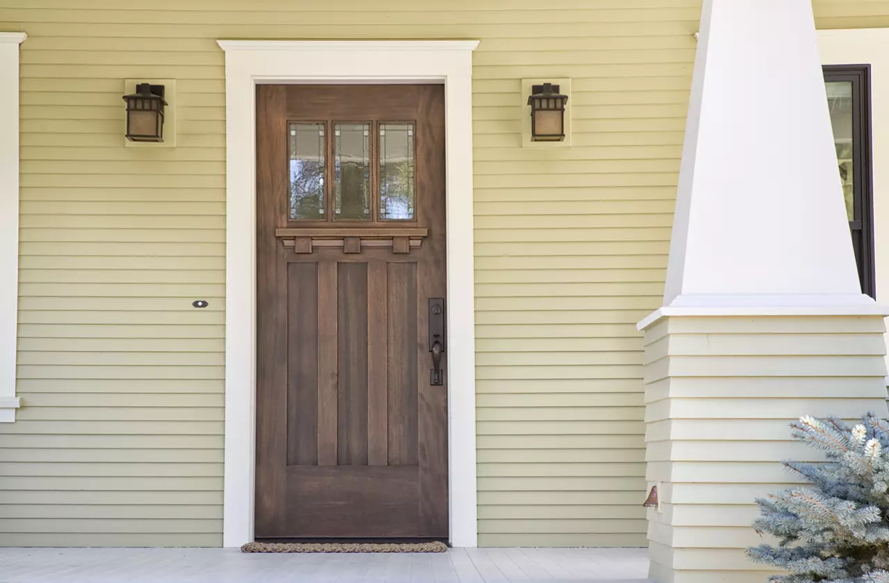 Closed wooden door of a home with yellow siding